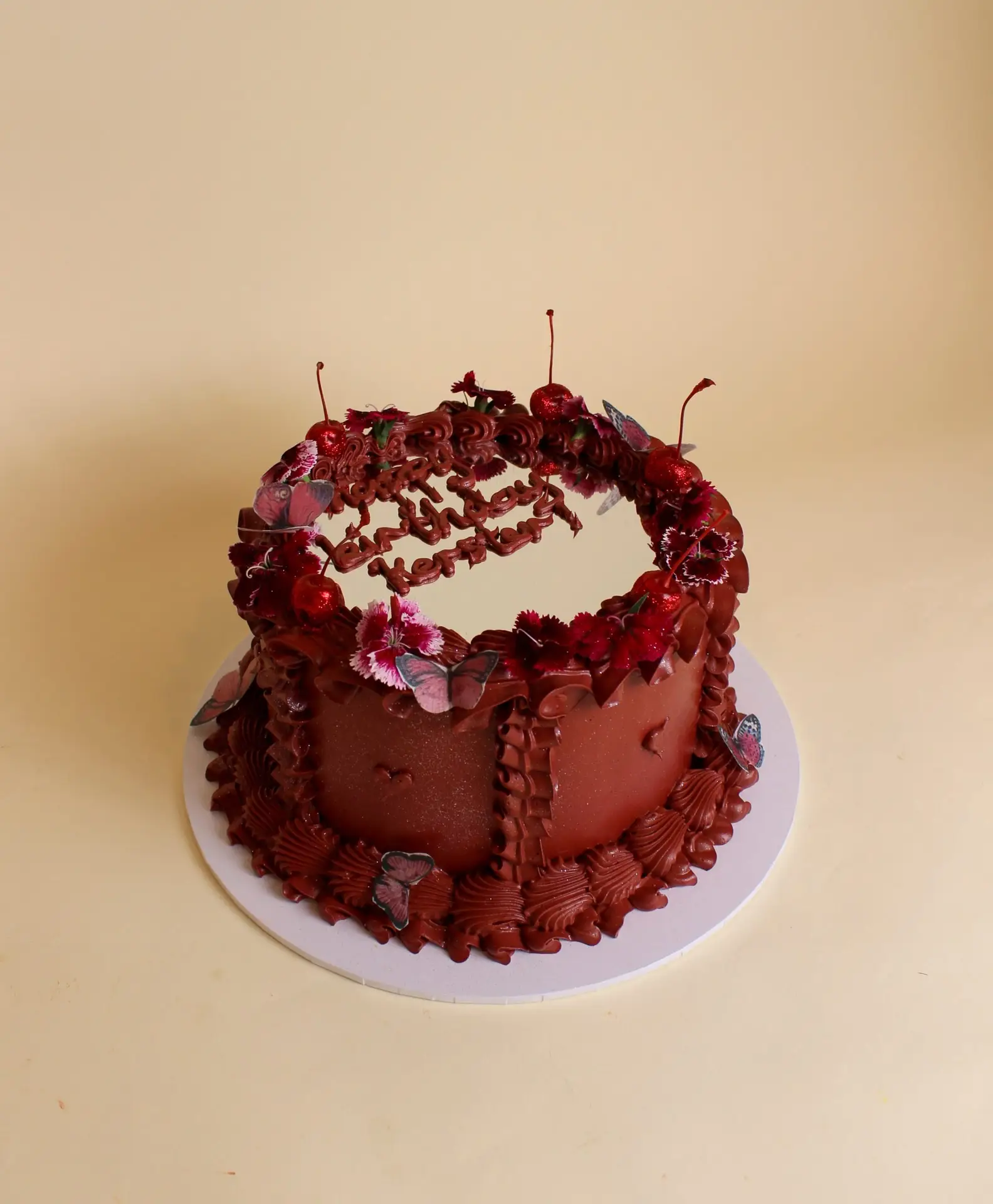 Round chocolate cake decorated with flowers and chocolate details on a white cake board. mirror cake, selfie cake, vintage cake, retro cake, birthday cake, teen cake