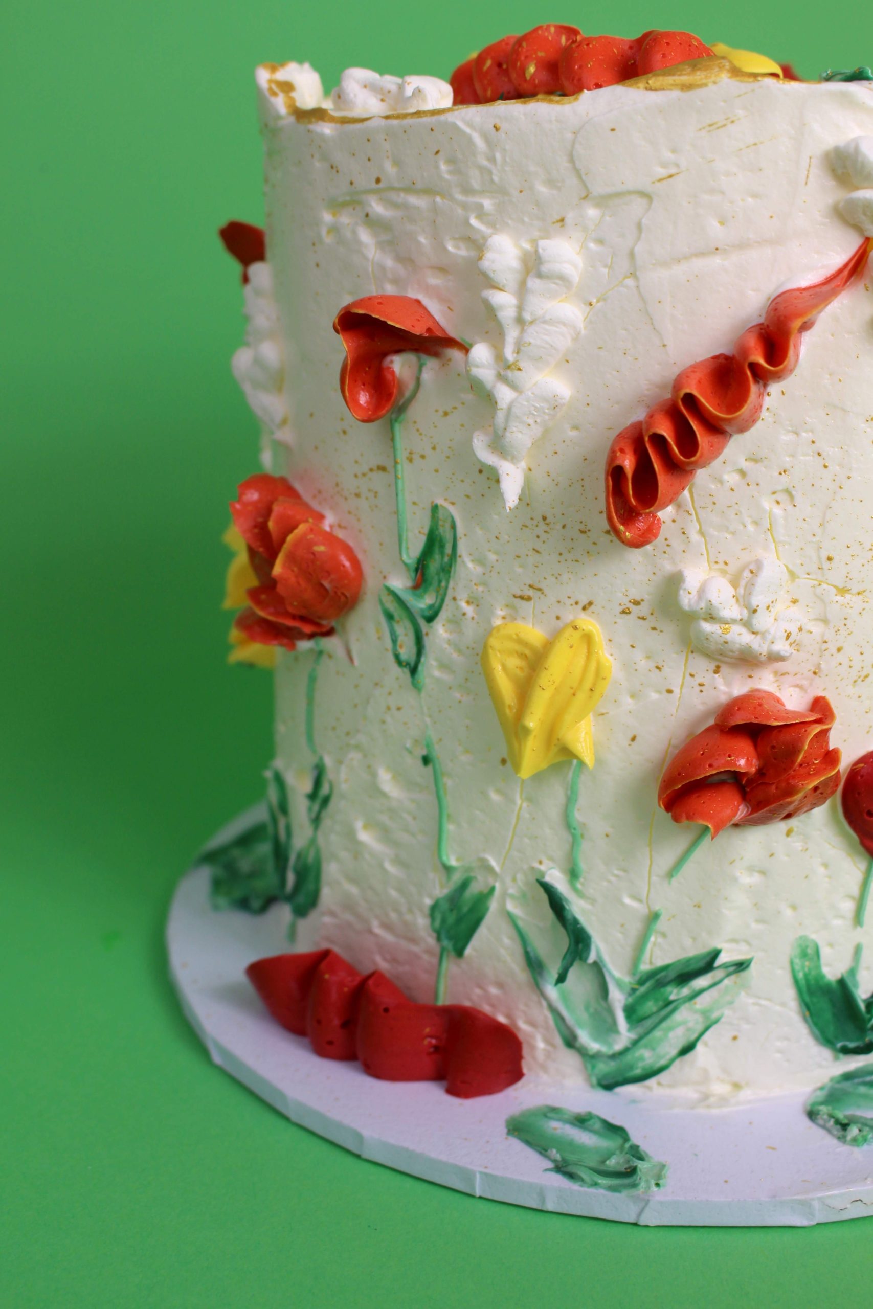 A cake decorated with colorful floral designs made of icing on a green background. floral cake, floral piping, birthday cake, celebration cake